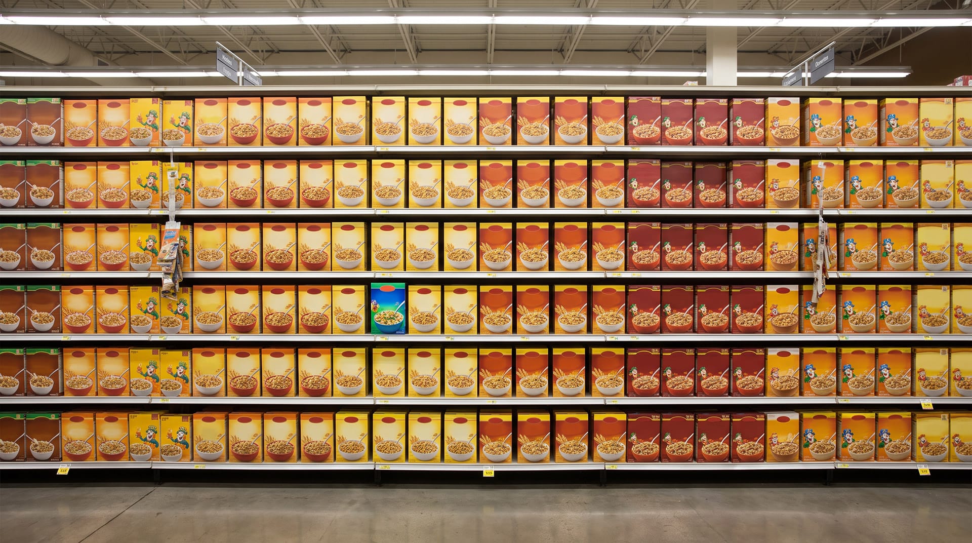Raft de supermarket cu numeroase cutii de cereale în culori similare și un singur produs contrastant care atrage atenția shopperului